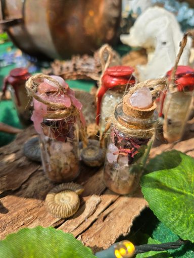 fioles talisman Bouteilles en verre entourées de lierre et d'éléments naturels, sur un fond en bois.