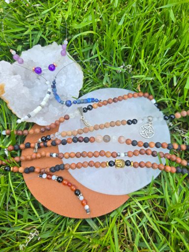 Bracelets de chevilles Bijoux artisanaux en perles, disposés sur une surface avec une pierre précieuse, sur herbe.