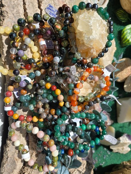 Bracelets personalisés Collier en perles colorées disposés autour de cristaux sur une surface texturée.